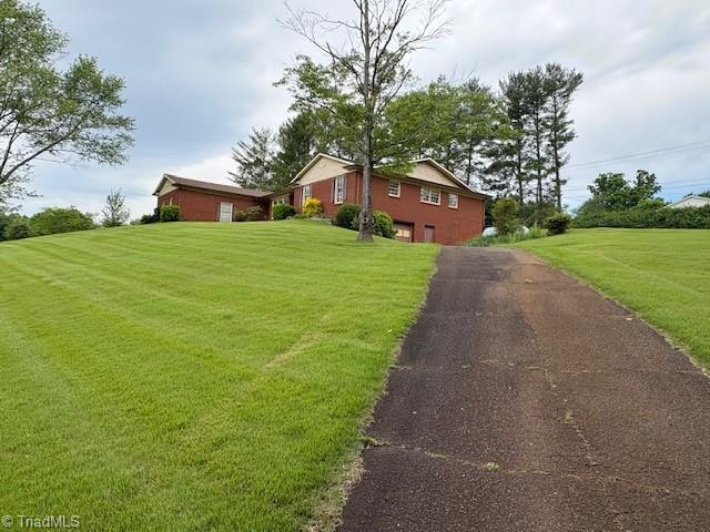 view of front of home featuring driveway, a garage, and a front yard