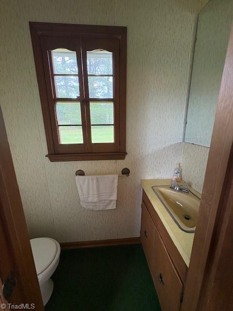 bathroom featuring healthy amount of natural light, vanity, and toilet