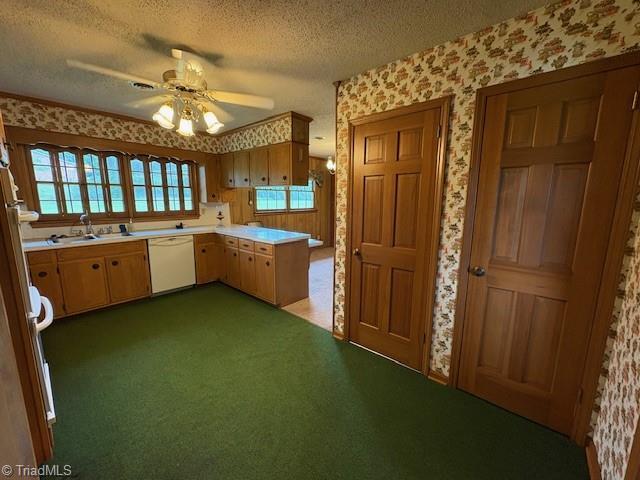 kitchen featuring dishwasher, wallpapered walls, light countertops, a textured ceiling, and a sink