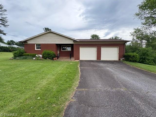 ranch-style home featuring an attached garage, a front yard, asphalt driveway, and brick siding