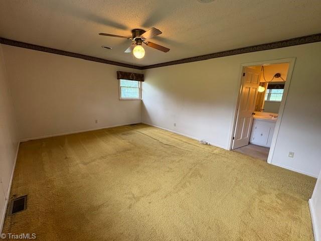 empty room featuring a ceiling fan, crown molding, carpet flooring, and baseboards