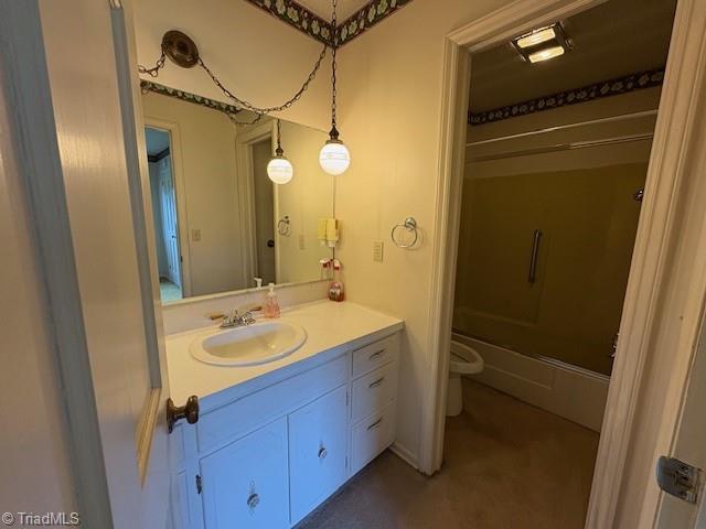 full bath with toilet, vanity, and shower / bath combination with glass door