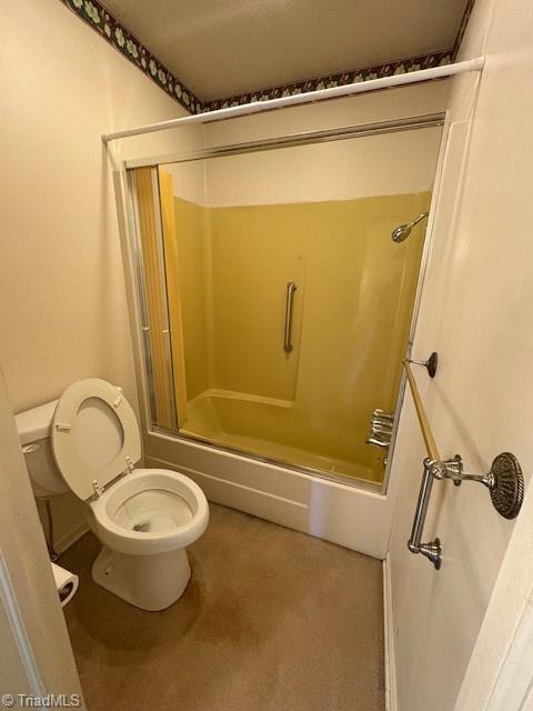 bathroom featuring a shower with door and toilet