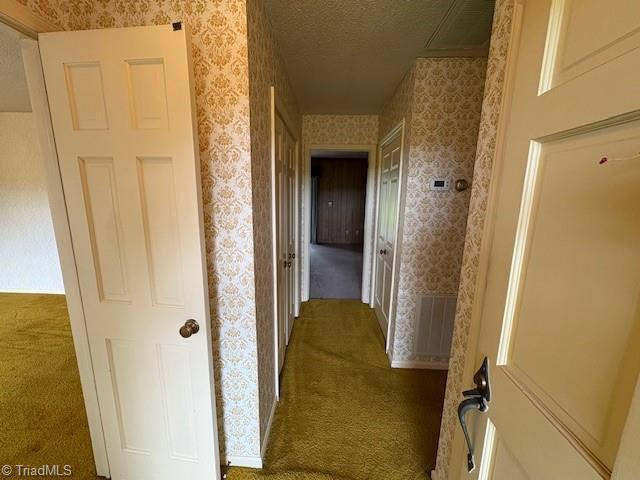 hallway featuring wallpapered walls, carpet floors, and a textured ceiling