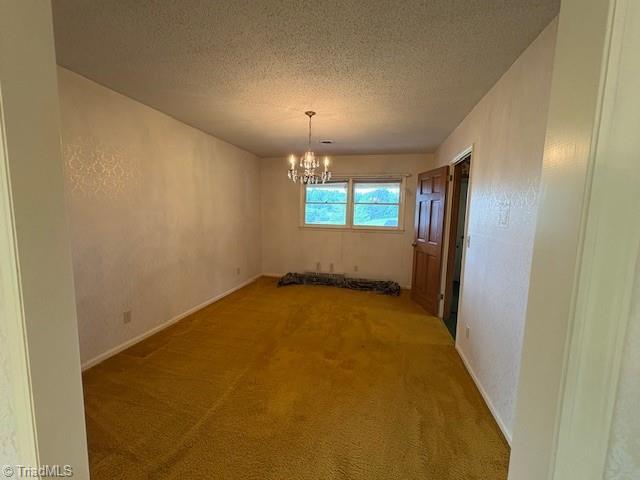 unfurnished dining area with a chandelier, light carpet, a textured ceiling, and baseboards