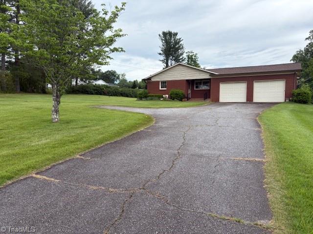 ranch-style home with driveway, a garage, and a front lawn