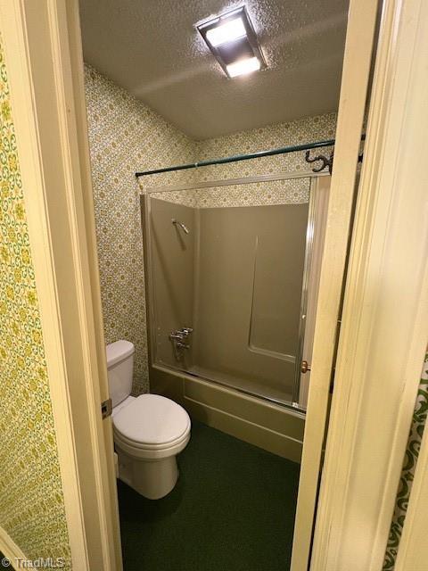 full bathroom with toilet, a textured ceiling, and shower / washtub combination