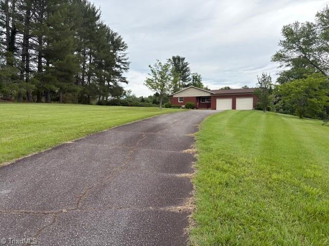 view of front of home featuring an attached garage, driveway, and a front lawn