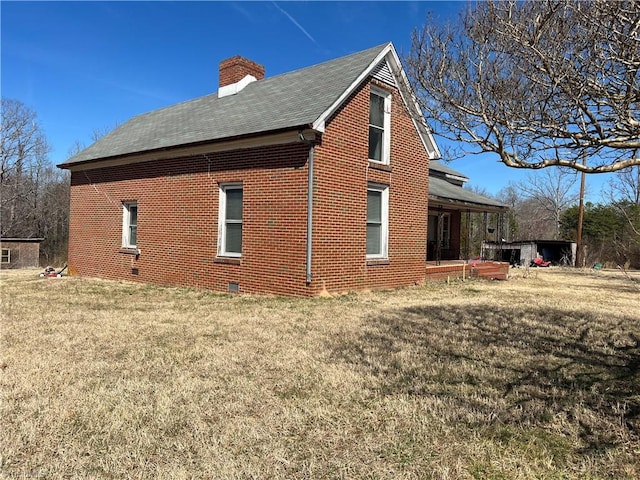 view of side of home with crawl space, a yard, brick siding, and a chimney