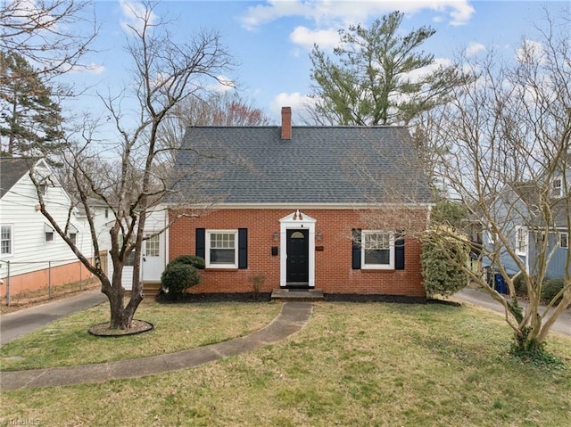 cape cod house with brick siding, a chimney, a front lawn, and roof with shingles