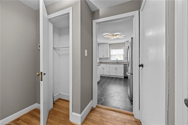 hall with a sink, baseboards, and dark wood finished floors