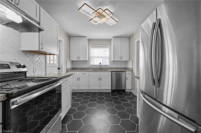 kitchen featuring a sink, under cabinet range hood, appliances with stainless steel finishes, white cabinets, and dark tile patterned flooring