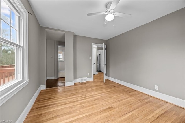 unfurnished bedroom featuring multiple windows, baseboards, and light wood-style floors