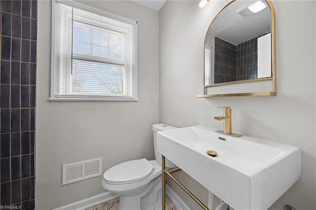 bathroom with toilet, visible vents, and a sink