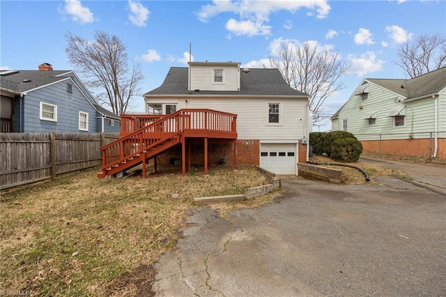 back of property featuring fence, a wooden deck, stairs, driveway, and an attached garage