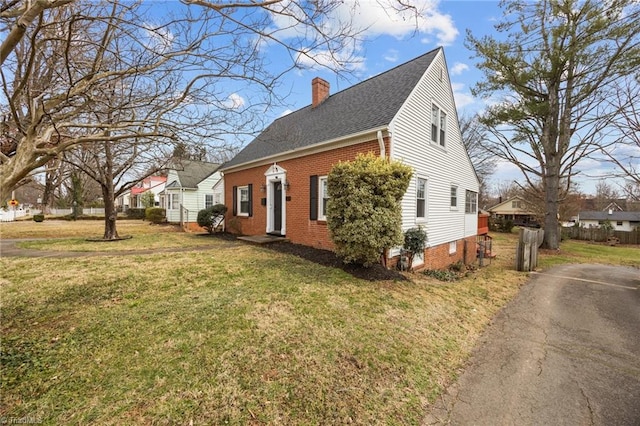 view of home's exterior with a lawn, brick siding, roof with shingles, and a chimney