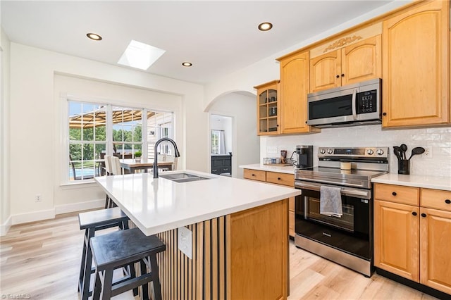 2264 Loflin Farlow Ln, Sophia, NC 27350 - kitchen featuring appliances with stainless steel finishes, light wood-style flooring, a kitchen breakfast bar, decorative backsplash, and light countertops