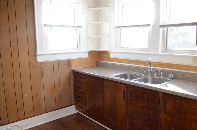 kitchen featuring open shelves, wooden walls, and a sink