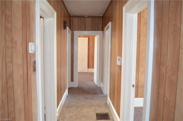 hall featuring light carpet, visible vents, and wood walls