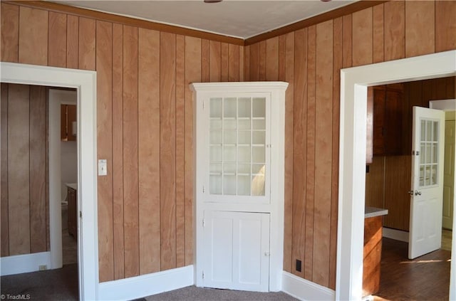 unfurnished room with wood walls and baseboards
