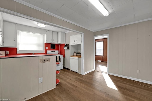 kitchen with white appliances, wooden walls, white cabinets, ornamental molding, and dark hardwood / wood-style floors