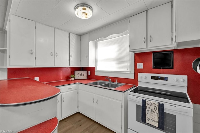 kitchen featuring hardwood / wood-style floors, sink, electric range, and white cabinetry