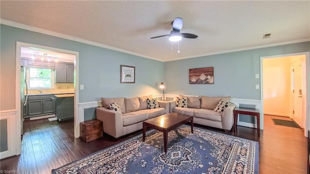 1721 Abbottsford Dr, Kernersville, NC 27284 - living area featuring dark wood-type flooring, ornamental molding, a ceiling fan, wainscoting, and a textured ceiling