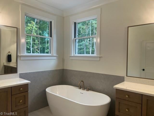 bathroom with vanity, a tub to relax in, and tile walls