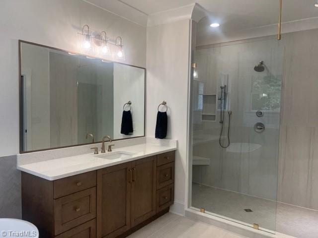 bathroom featuring vanity, ornamental molding, and tiled shower