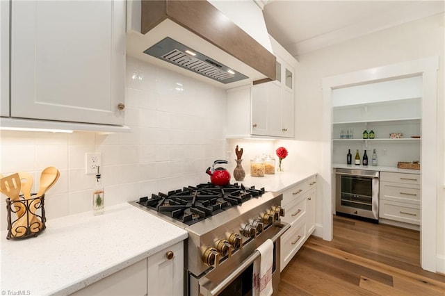 kitchen with white cabinets, high end stainless steel range, wall chimney range hood, and beverage cooler