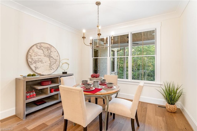 dining room featuring hardwood / wood-style flooring, an inviting chandelier, and crown molding