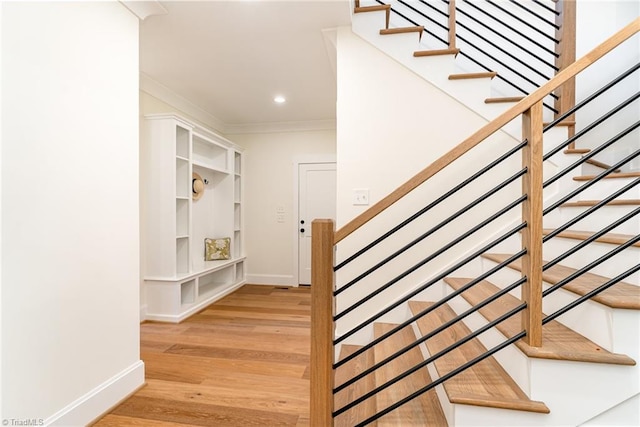 stairs with hardwood / wood-style flooring and ornamental molding