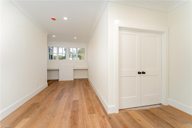 hallway with crown molding and light wood-type flooring