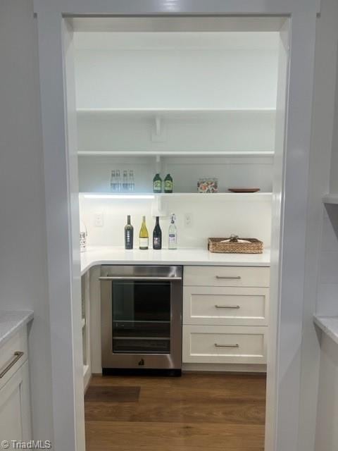 bar featuring white cabinets, wine cooler, and dark wood-type flooring