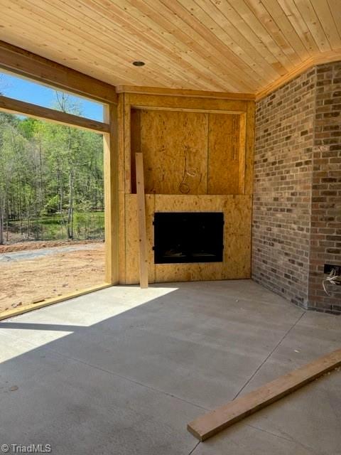 unfurnished living room with brick wall, a fireplace, concrete flooring, and wooden ceiling