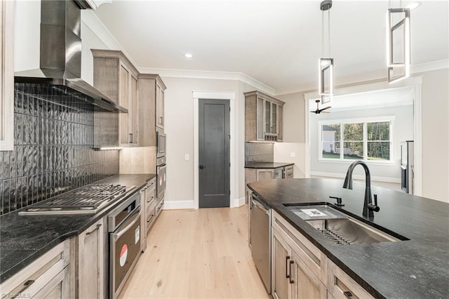 kitchen with stainless steel appliances, hanging light fixtures, sink, wall chimney range hood, and crown molding