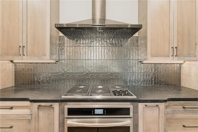 kitchen with appliances with stainless steel finishes, wall chimney exhaust hood, tasteful backsplash, and light brown cabinets