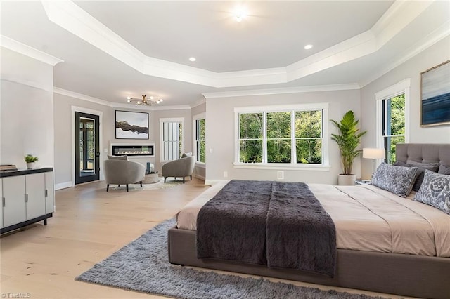 bedroom featuring a raised ceiling, light hardwood / wood-style flooring, and crown molding