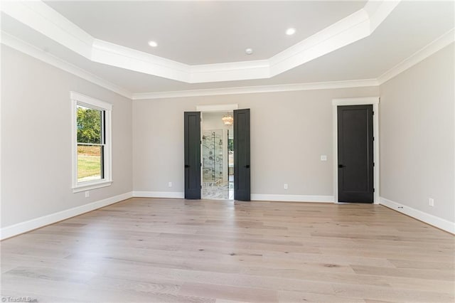 spare room with a tray ceiling, ornamental molding, and light hardwood / wood-style flooring