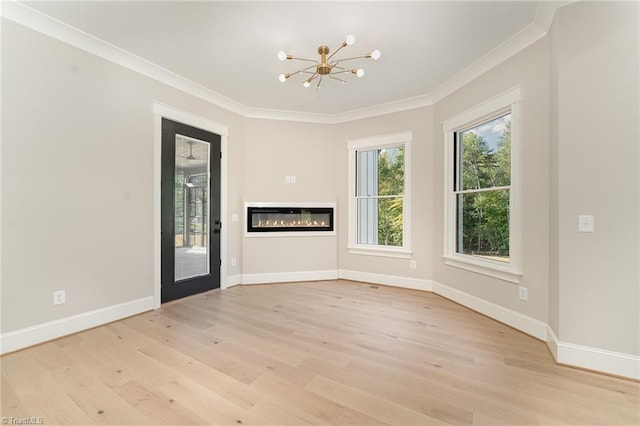 empty room with ornamental molding, light wood-type flooring, and a chandelier