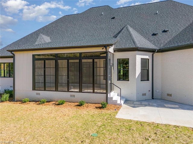 rear view of property with a lawn, a patio, and a sunroom