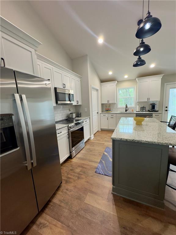 2968 Tobaccoville Rd, Tobaccoville, NC 27050 - kitchen featuring white cabinets, a sink, appliances with stainless steel finishes, a kitchen island, and lofted ceiling