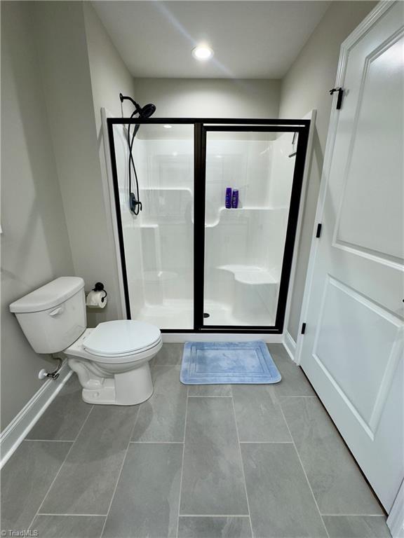 2968 Tobaccoville Rd, Tobaccoville, NC 27050 - bathroom featuring tile patterned floors, toilet, a shower stall, and baseboards