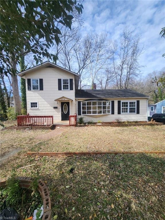 view of front of home featuring a deck, a front lawn, and a chimney