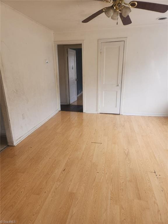 spare room featuring ceiling fan, visible vents, baseboards, and light wood-style flooring