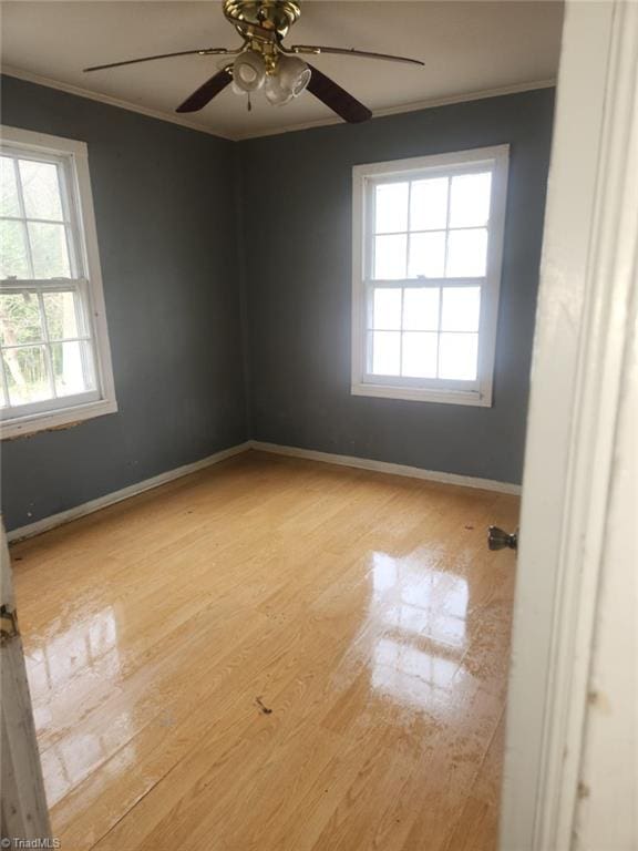 empty room featuring wood finished floors, a ceiling fan, baseboards, and ornamental molding