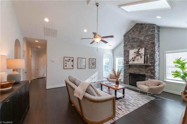 living room with ceiling fan, dark hardwood / wood-style floors, a stone fireplace, and high vaulted ceiling