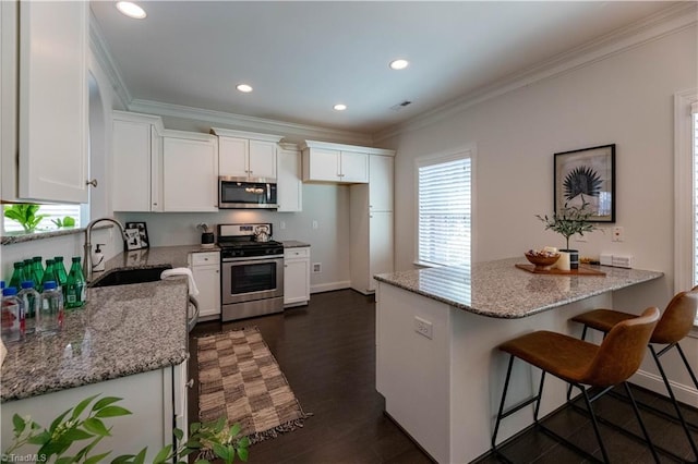 kitchen with white cabinets, sink, light stone counters, and stainless steel appliances