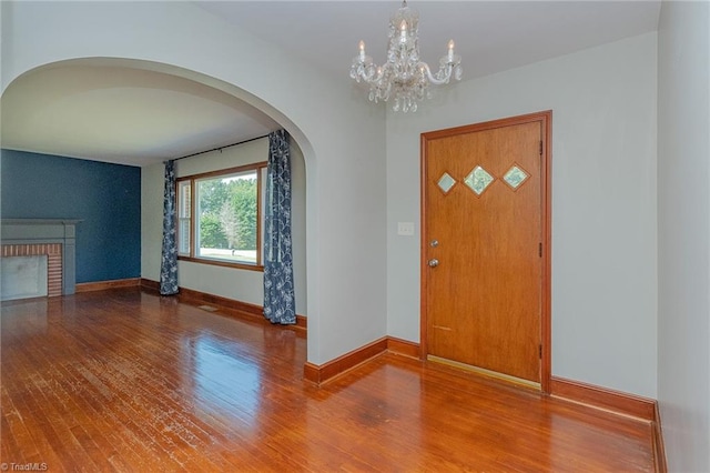 entrance foyer featuring an inviting chandelier, hardwood / wood-style floors, and a fireplace