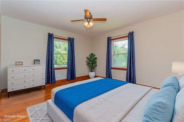 bedroom with multiple windows, hardwood / wood-style floors, and ceiling fan